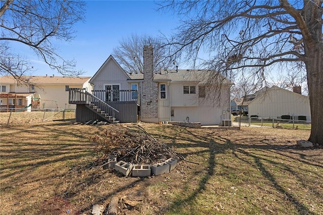 back of property with stairway, a wooden deck, a chimney, and fence