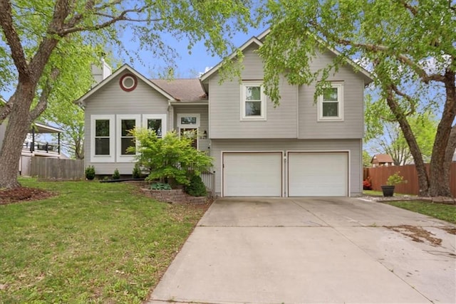 tri-level home with a garage, fence, driveway, and a front yard