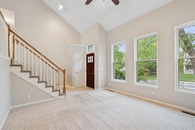 carpeted entrance foyer featuring a ceiling fan, visible vents, baseboards, high vaulted ceiling, and stairs