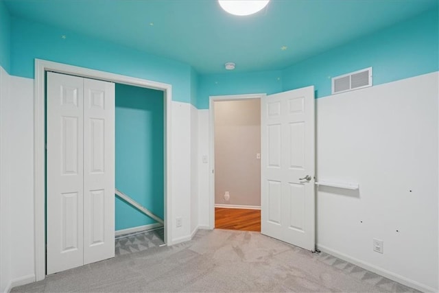 unfurnished bedroom featuring carpet floors, baseboards, a closet, and visible vents