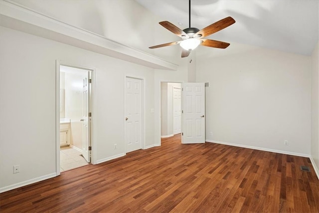 unfurnished bedroom featuring lofted ceiling, wood finished floors, baseboards, ceiling fan, and ensuite bath