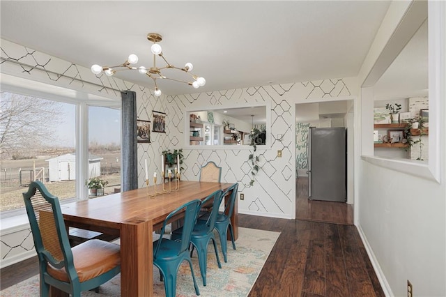 dining area featuring wallpapered walls, dark wood finished floors, baseboards, and a chandelier