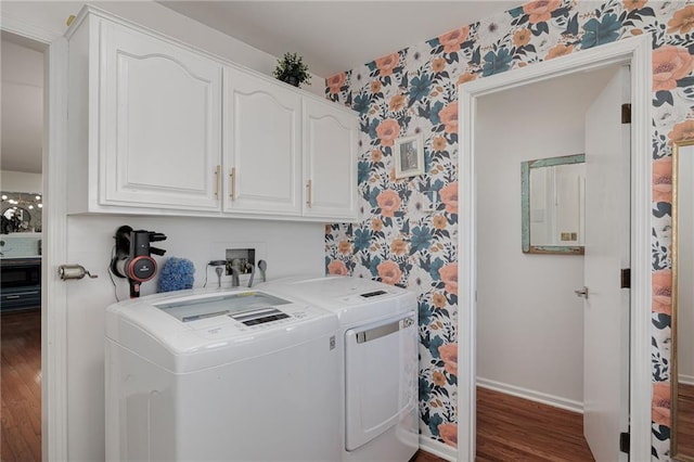 laundry room with washing machine and clothes dryer, wallpapered walls, baseboards, wood finished floors, and cabinet space