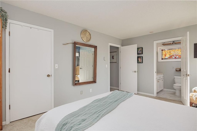 bedroom with ensuite bath, baseboards, and light carpet