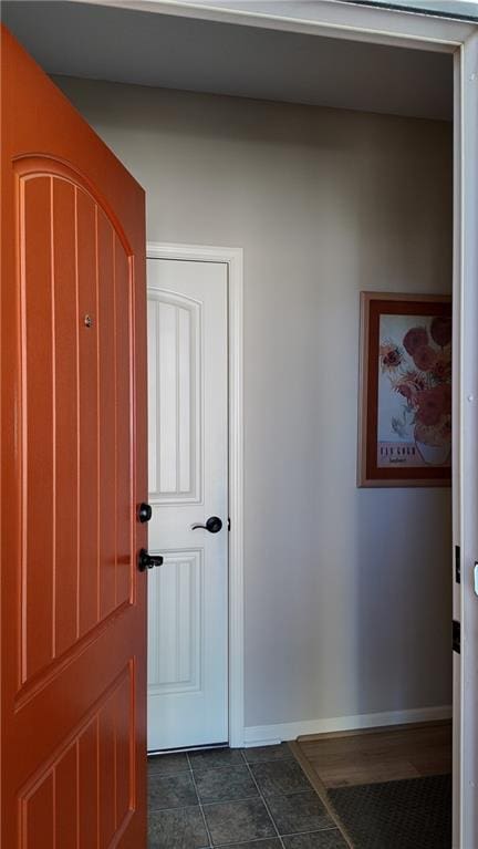 hallway with baseboards and dark tile patterned flooring