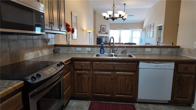 kitchen featuring a sink, vaulted ceiling, appliances with stainless steel finishes, pendant lighting, and a chandelier