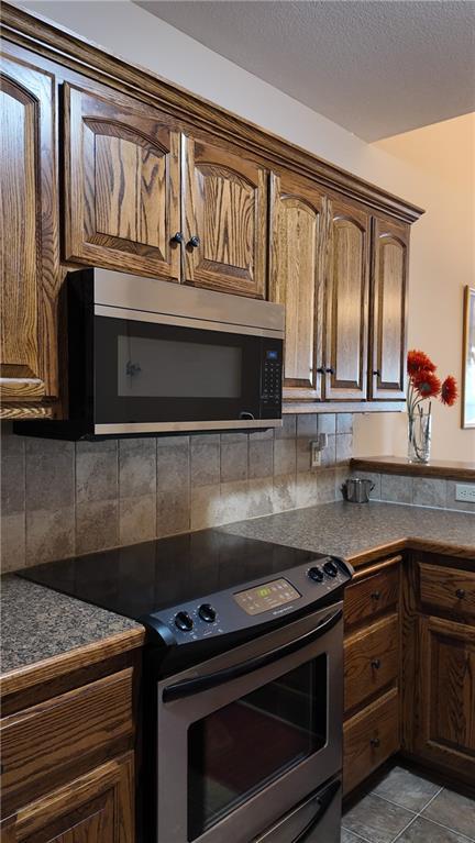 kitchen featuring a textured ceiling, dark countertops, tasteful backsplash, and stainless steel appliances