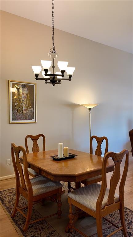 dining area featuring light wood-style floors, an inviting chandelier, and vaulted ceiling