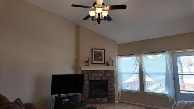 living room with wood finished floors, a fireplace, baseboards, ceiling fan, and vaulted ceiling