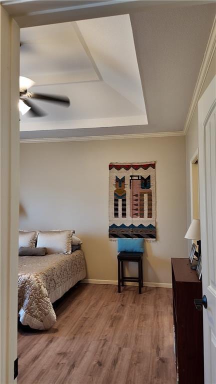 bedroom featuring a ceiling fan, wood finished floors, baseboards, and ornamental molding