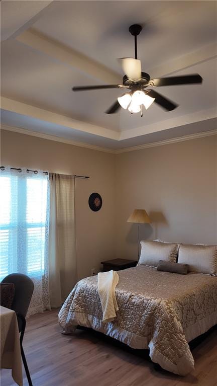 bedroom featuring a tray ceiling, wood finished floors, and ornamental molding