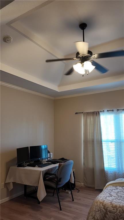 bedroom with a raised ceiling, crown molding, wood finished floors, and ceiling fan