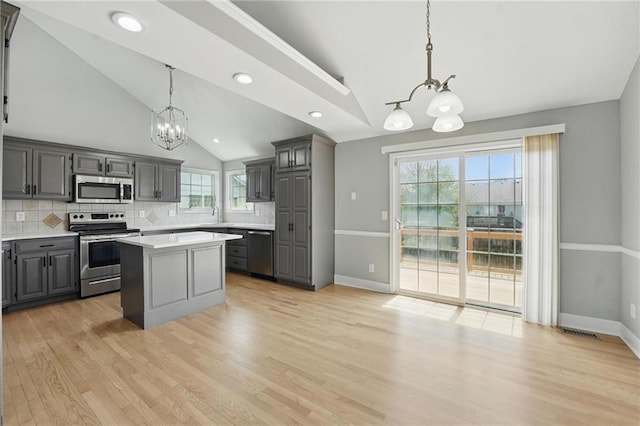 12203 E 214th Ter, Peculiar, MO 64078 - kitchen featuring a chandelier, appliances with stainless steel finishes, gray cabinets, vaulted ceiling, and tasteful backsplash