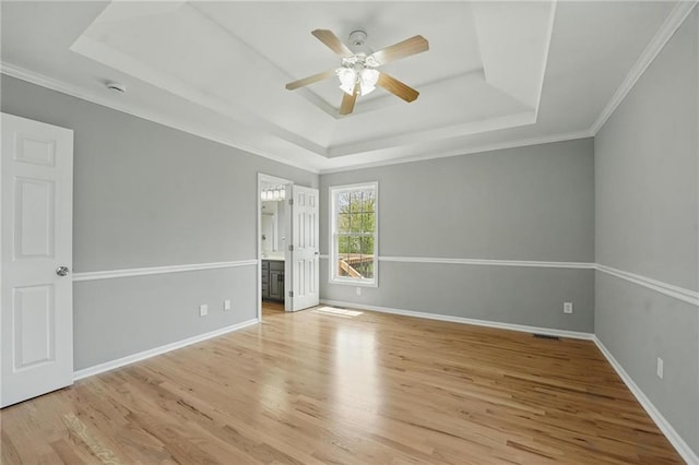 12203 E 214th Ter, Peculiar, MO 64078 - unfurnished bedroom featuring a tray ceiling, wood finished floors, baseboards, ornamental molding, and ensuite bath