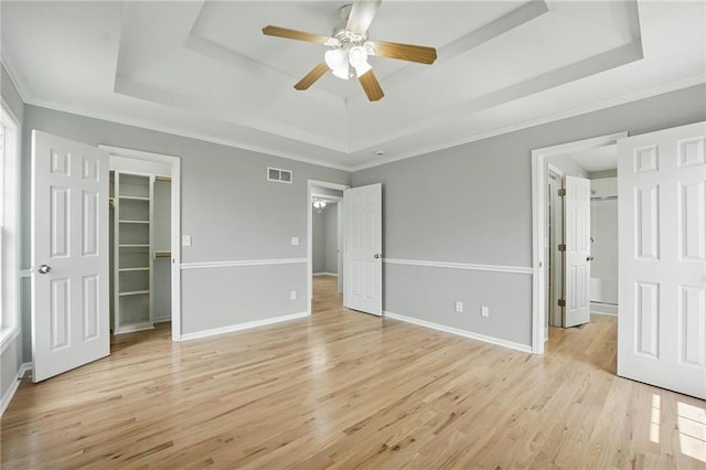 12203 E 214th Ter, Peculiar, MO 64078 - unfurnished bedroom with a raised ceiling, a spacious closet, light wood-style flooring, a closet, and baseboards