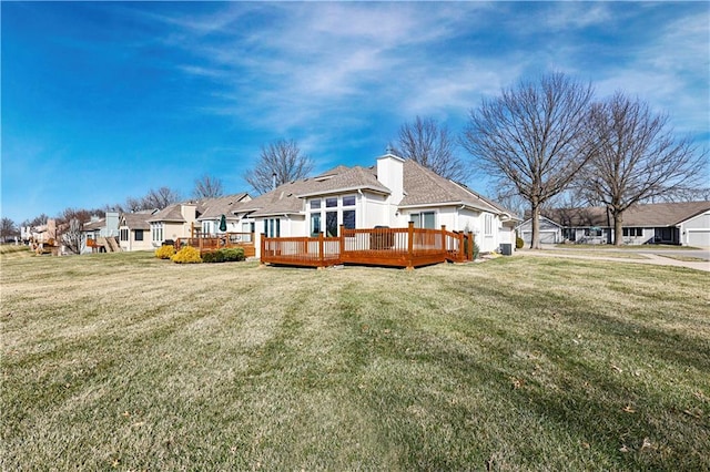 rear view of house featuring a residential view, a wooden deck, a yard, and a shingled roof