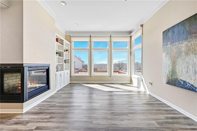 unfurnished living room with crown molding, built in features, wood finished floors, and a multi sided fireplace