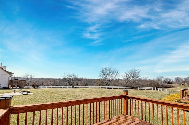 wooden terrace with a rural view, a lawn, and fence