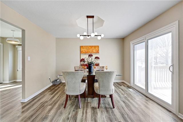 dining room with baseboards, a notable chandelier, and wood finished floors