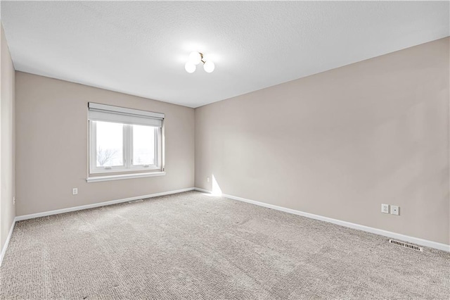 carpeted empty room with visible vents, a textured ceiling, and baseboards