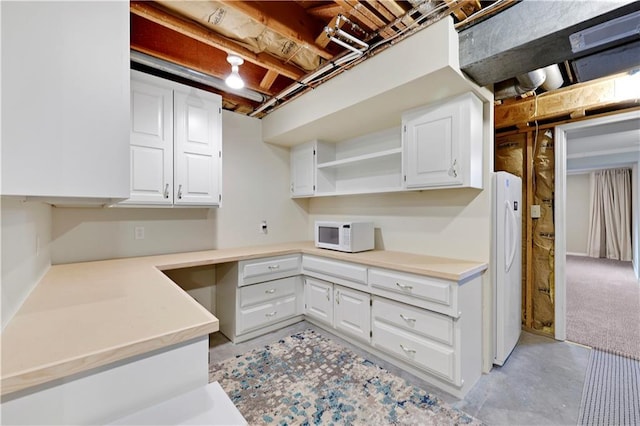 kitchen with white appliances, built in study area, open shelves, light countertops, and white cabinets