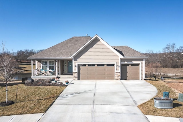 view of front facade featuring driveway, stone siding, a porch, roof with shingles, and a garage