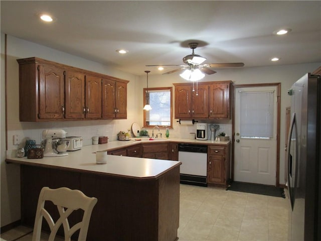 kitchen with freestanding refrigerator, a peninsula, light countertops, decorative backsplash, and dishwasher