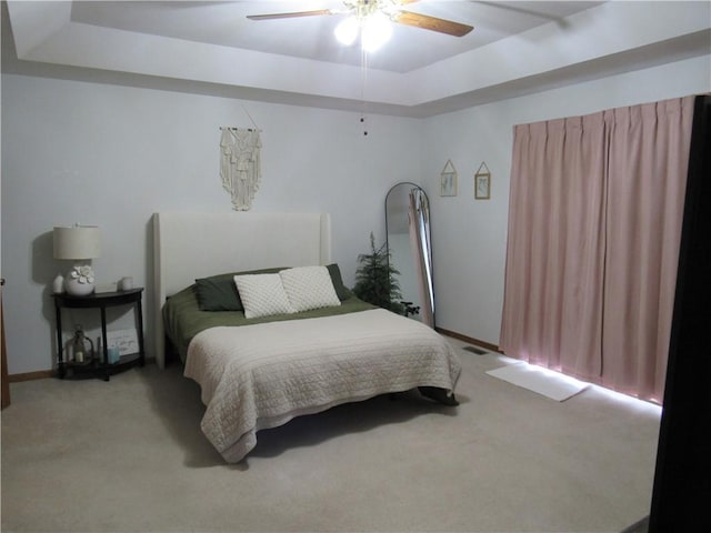 bedroom with a raised ceiling, a ceiling fan, baseboards, and light carpet