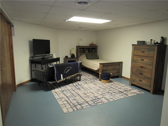 bedroom with a drop ceiling, baseboards, and finished concrete floors