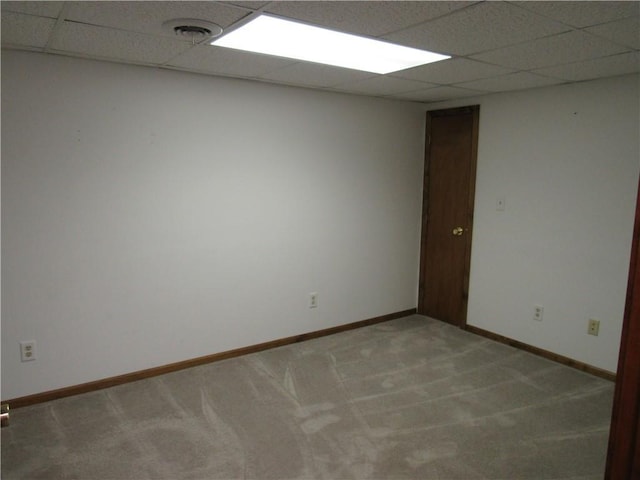 spare room with light carpet, a paneled ceiling, and baseboards