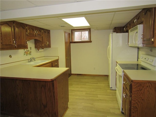 kitchen featuring white appliances, baseboards, light wood-style flooring, a sink, and light countertops