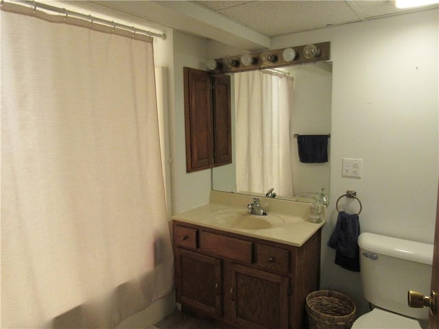 bathroom featuring vanity, shower / tub combo with curtain, toilet, and a drop ceiling