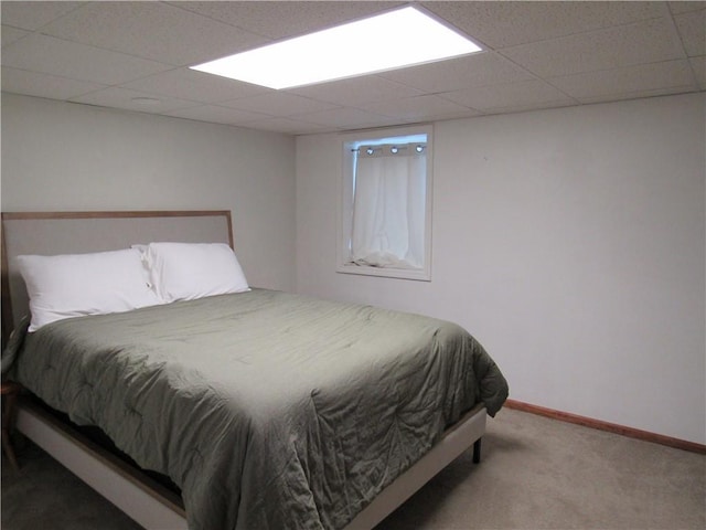 carpeted bedroom with baseboards and a drop ceiling