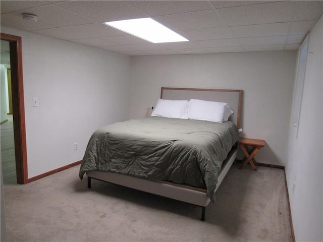 bedroom with a drop ceiling, baseboards, and carpet floors