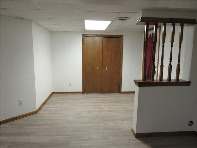 spare room featuring light wood-type flooring, a drop ceiling, baseboards, and visible vents