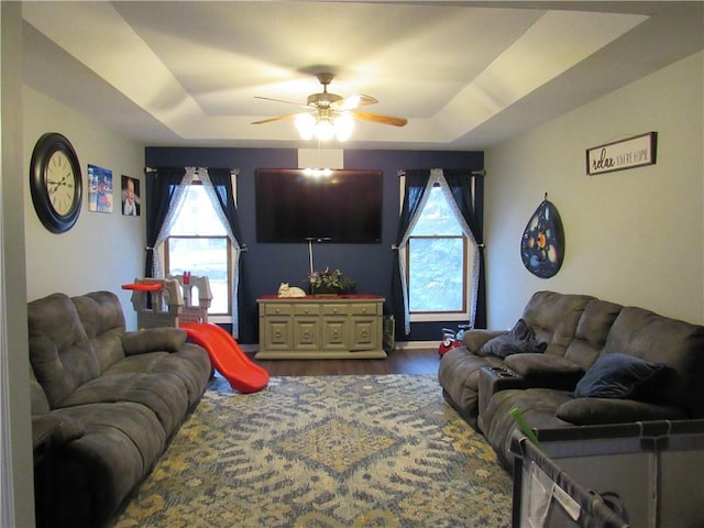 living room with a tray ceiling, wood finished floors, and ceiling fan