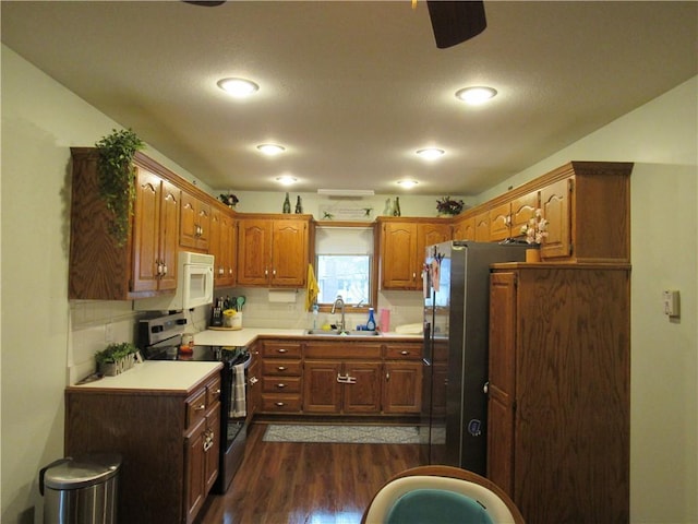 kitchen featuring a sink, backsplash, dark wood-style floors, stainless steel appliances, and light countertops