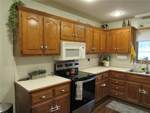 kitchen with a sink, white microwave, stainless steel electric range, and light countertops