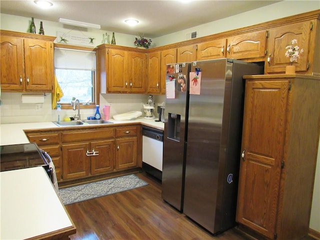 kitchen with dark wood-style floors, stainless steel fridge with ice dispenser, a sink, dishwasher, and brown cabinets