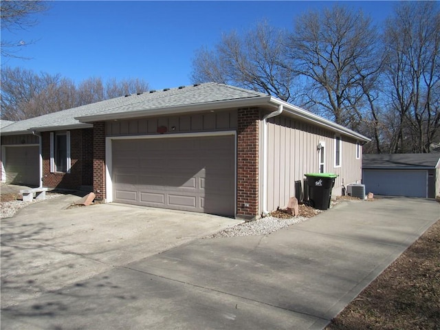 view of side of home featuring an attached garage, brick siding, board and batten siding, and driveway