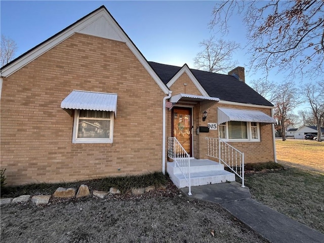 view of front of home featuring brick siding and a chimney