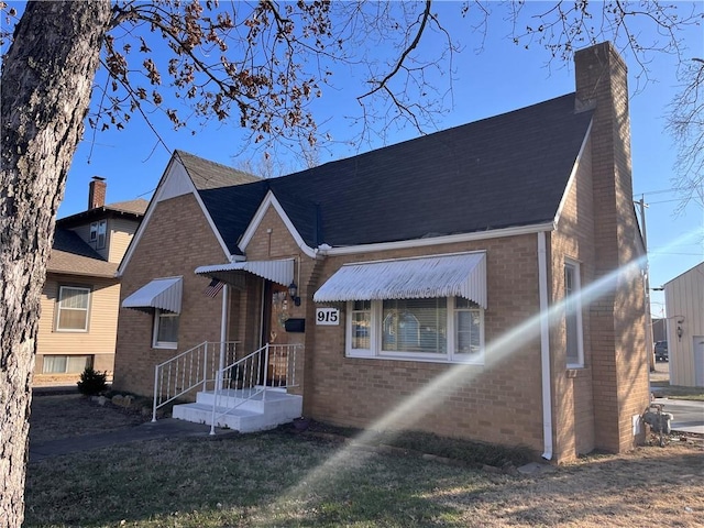 view of front of property featuring brick siding and a chimney