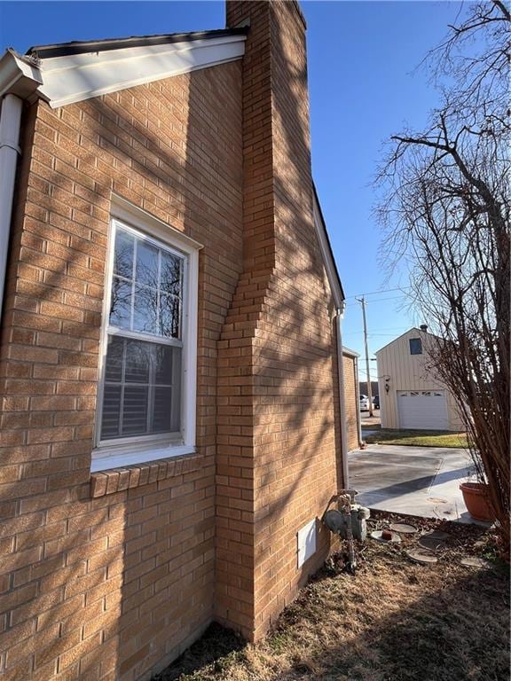 view of side of property with brick siding, a chimney, and an outdoor structure