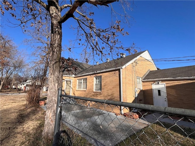 view of side of home with brick siding and fence