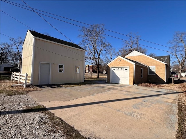 detached garage featuring concrete driveway and fence