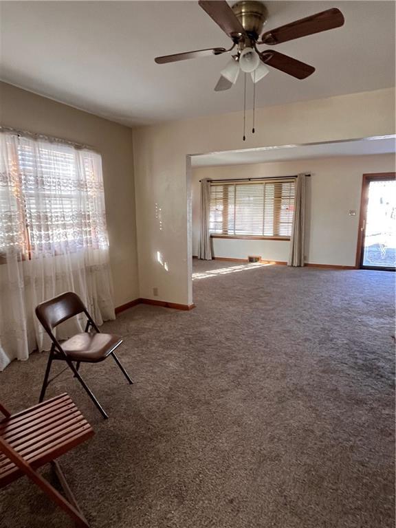 unfurnished room featuring a healthy amount of sunlight, a ceiling fan, baseboards, and carpet floors