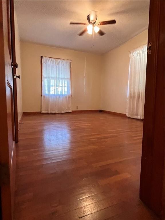empty room with ceiling fan, baseboards, and wood finished floors