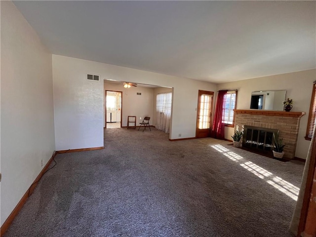 unfurnished living room featuring visible vents, carpet flooring, a brick fireplace, and baseboards