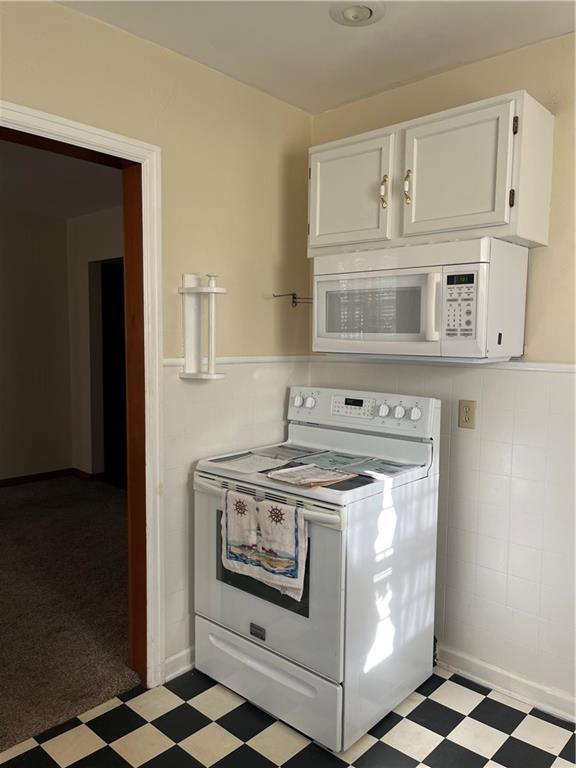 kitchen featuring white appliances, light floors, and white cabinetry