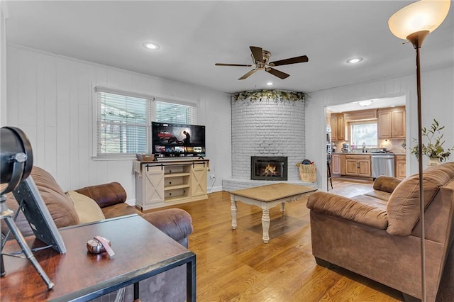 living room with recessed lighting, a brick fireplace, ceiling fan, and light wood finished floors